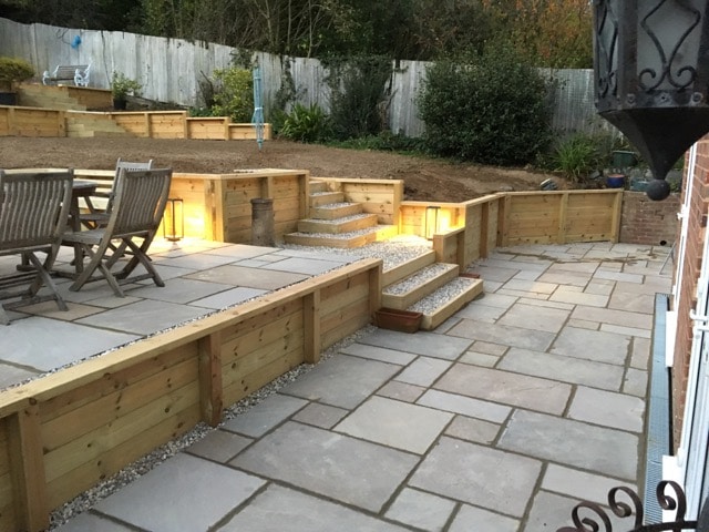 Sandstone paving with terracing and lawn areas to create useful space in a sloping garden with atmospheric outdoor lighting Tunbridge Wells