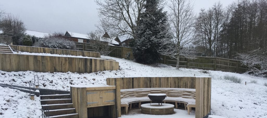 Fire pit in winter garden with bespoke steam bent oak bench Rotherfield Sussex