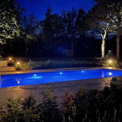 View towards woods of outdoor pool area with trees uplit garden design Sussex Kent